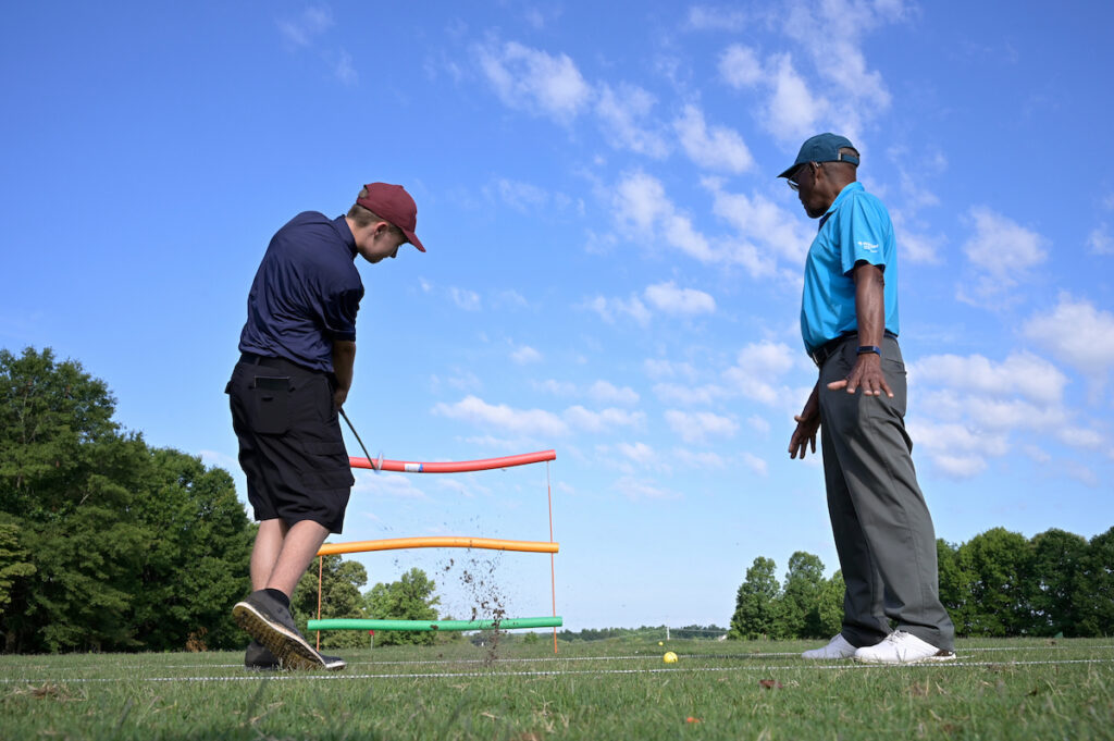 A coach works with a player on a chipping drill